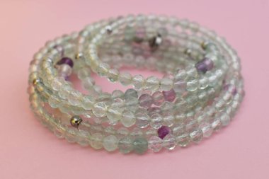 Pembe arka planda boncuklardan yapılmış bilezik. Kadınlar için bileklik.