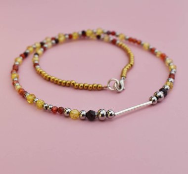 Pembe arkaplandaki boncuklardan yapılmış kolye, yakın plan.