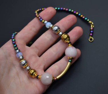 Koyu bir arkaplanda farklı renkte boncuklarla çevrili bir el.