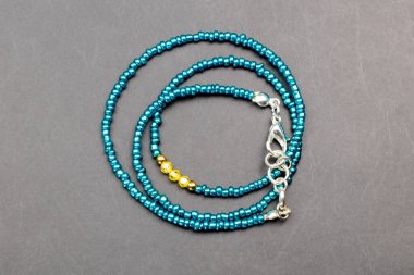 Siyah arkaplanda mavi ve sarı boncuklu kolye.