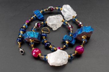 Siyah zemin üzerinde çok renkli taşlardan yapılmış bir kolye