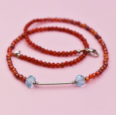 Mücevherler. Pembe arka planda kırmızı boncuklardan yapılmış bilezik.