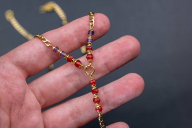 Bir adamın elindeki kolye koyu bir arka planda. Yakın plan.