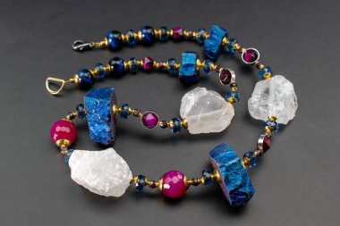 Siyah bir arkaplanda değerli taşlardan yapılmış bir kolye.