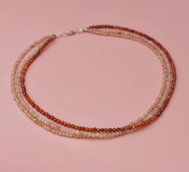 Pembe arka planda boncuklu kolye. Kadınlar için bileklik.