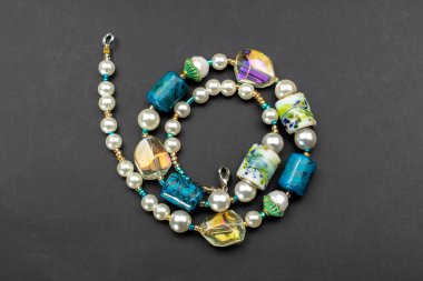 Siyah arkaplanda boncuklardan ve değerli taşlardan yapılmış bir kolye.