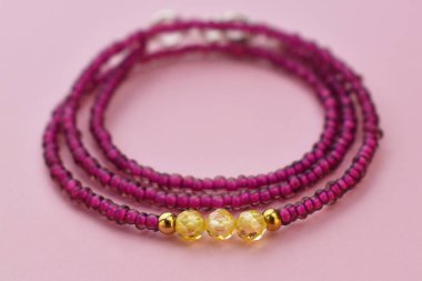 Pembe arka planda kolye. Doğal boncuklardan yapılmış bilezik..