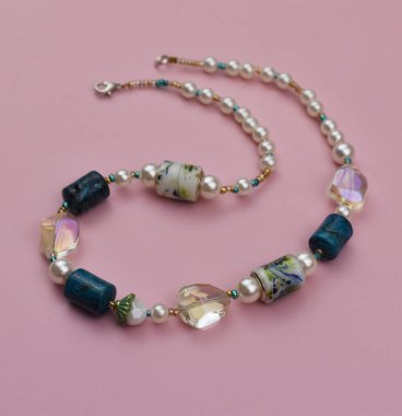 Pembe zemin üzerinde yarı değerli taşlardan yapılmış bir kolye.