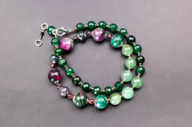 Gri arkaplanda farklı renkte boncuklardan yapılmış bilezik.