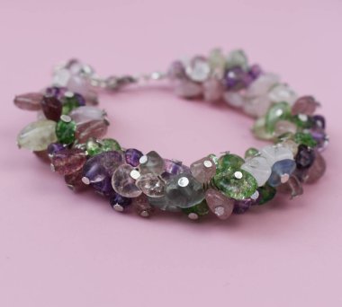 Pembe arka planda doğal taşlardan yapılmış kolye.