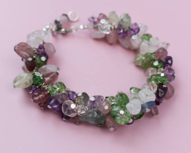 Pembe arka planda değerli taşları olan güzel bilezik.