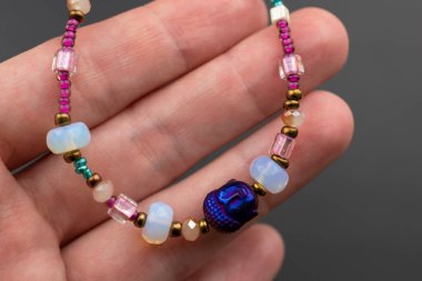Bir kadının elindeki çok renkli boncuklardan yapılmış kolye.