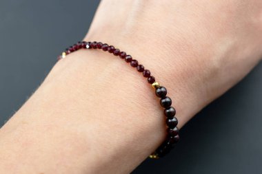 Gri arka planda bir kadının elindeki boncuklar..