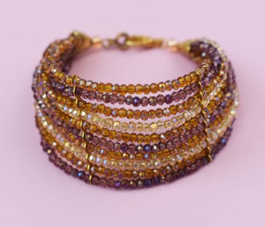 Pembe arka planda güzel altın bir bilezik, yakın plan. Lüks mücevherler.