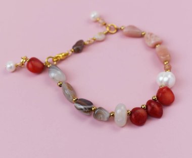 Pembe arka planda doğal taşlardan yapılmış kolye.