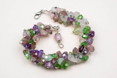 Beyaz arka planda çok renkli mücevherlerden yapılmış bilezik.