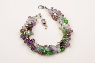 Beyaz arka planda çok renkli taşlardan yapılmış bir kolye.