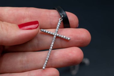 Siyah arka planda gümüş haç kadının elinde..