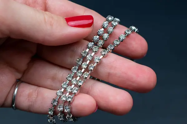 Jewelry and bijouterie. Woman hand with red manicure holding diamond earrings