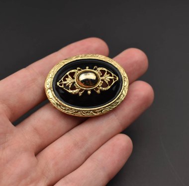 Siyah arka planda altın bir düğme var, yakın plan.