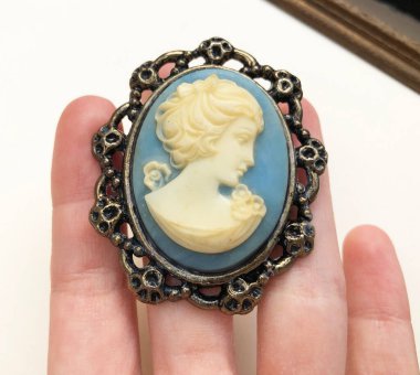 Elinde Bakire Meryem resmi olan mavi bir kolye var..