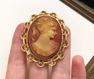 Kıymetli taş bir broşu elinde tutarken....