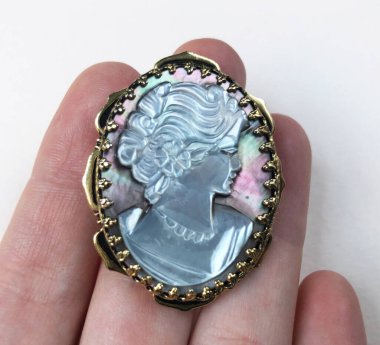 Elinde Bakire Meryem resmi olan antika bir madalyon var.