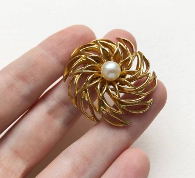 Altın broş beyaz arka planda, yakın planda.