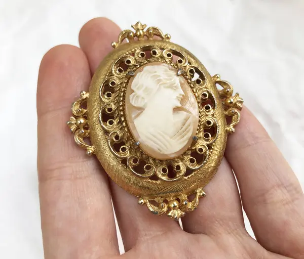 Elinde altın bir broş olan bir kadın.