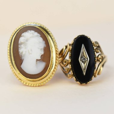 Beyaz arka planda siyah ve altın renkli mücevher yüzüğü.