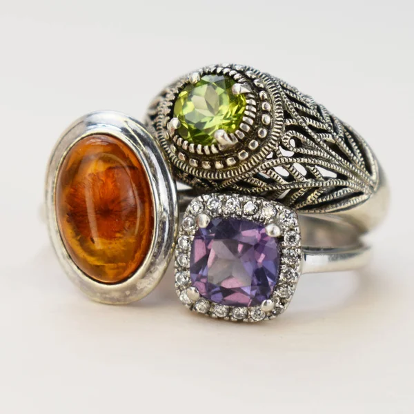 Beyaz zemin üzerinde çok renkli taşlar olan mücevher yüzüğü.