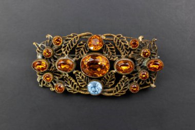 Siyah arka planda değerli taşları olan mücevher broşu..