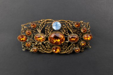 Siyah arka planda değerli taşları olan mücevher broşu..