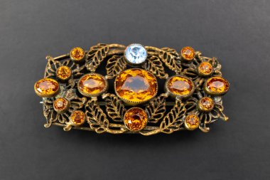 Siyah arka planda kehribar taşları olan bir broş. Mücevherler.