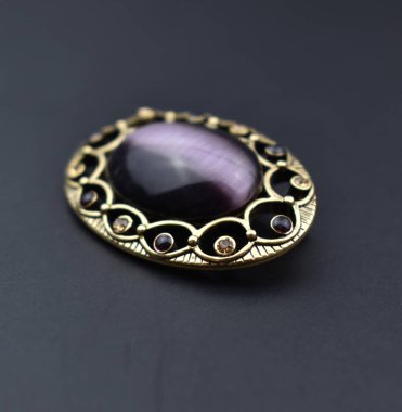 Siyah arka planda değerli taşlı klasik gümüş broş, yakın plan.