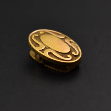 Siyah arka planda altın broş. Yakın plan. Stüdyo çekimi.