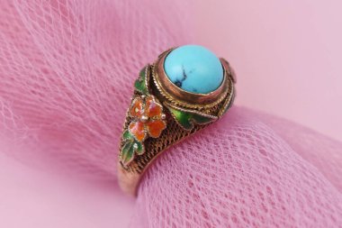 Pembe arka planda turkuaz taşlı mücevher yüzüğü..