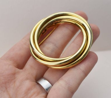 Elinde beyaz bir zemin üzerinde altın broş