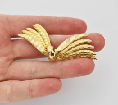 Beyaz arka planda altın bir kolye tutuyor, yakın plan.