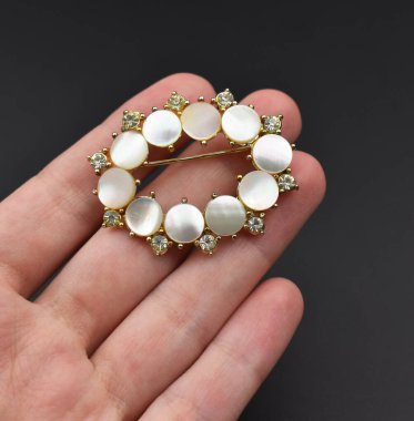 Koyu bir arka planda elde mücevher broşu.