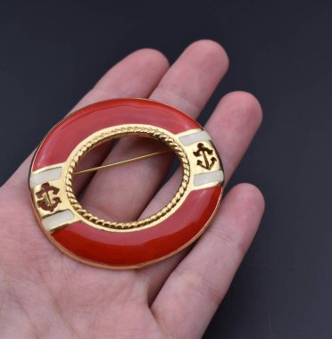 Koyu arka planda kırmızı broşlu bir el. Mücevher ve aksesuarlar..