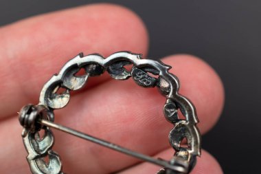 Elinde broş, arka planda koyu bir yakın plan.