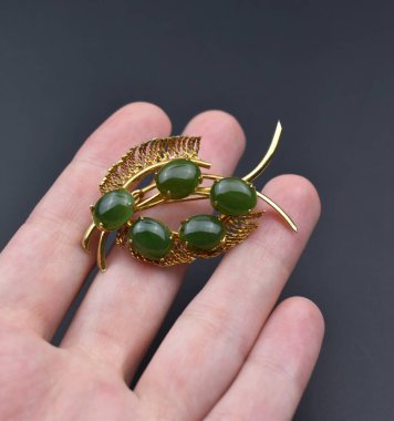 Elinde koyu renk bir arka planda bir çift yeşil küpe var..