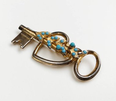 Beyaz arka planda mavi turkuaz taşlı altın anahtar.