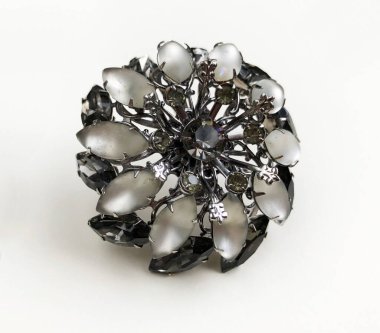 beyaz zemin üzerinde bir çiçek şeklinde broş.