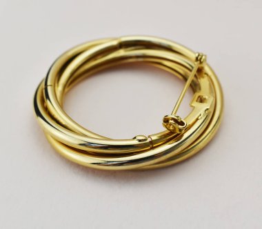 Beyaz arka planda altın bir broş. Lüks mücevherler..