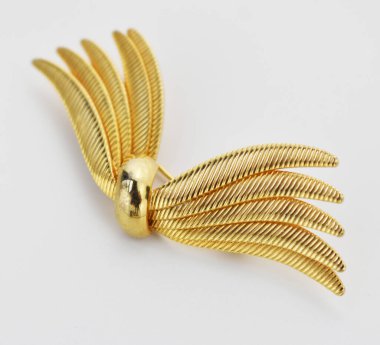 Beyaz arkaplanda altın broş, fotoğrafın yakın çekimi..