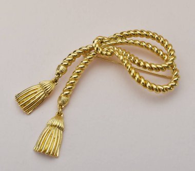 Beyaz arkaplanda altın broş, yakın plan fotoğraf.