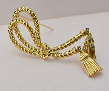 Beyaz arkaplanda altın broş, yakın plan, seçici odak