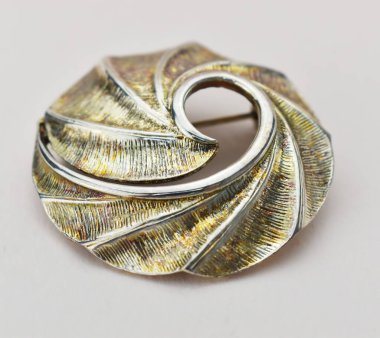 Beyaz arkaplanda gümüş bir broşa yakın plan.